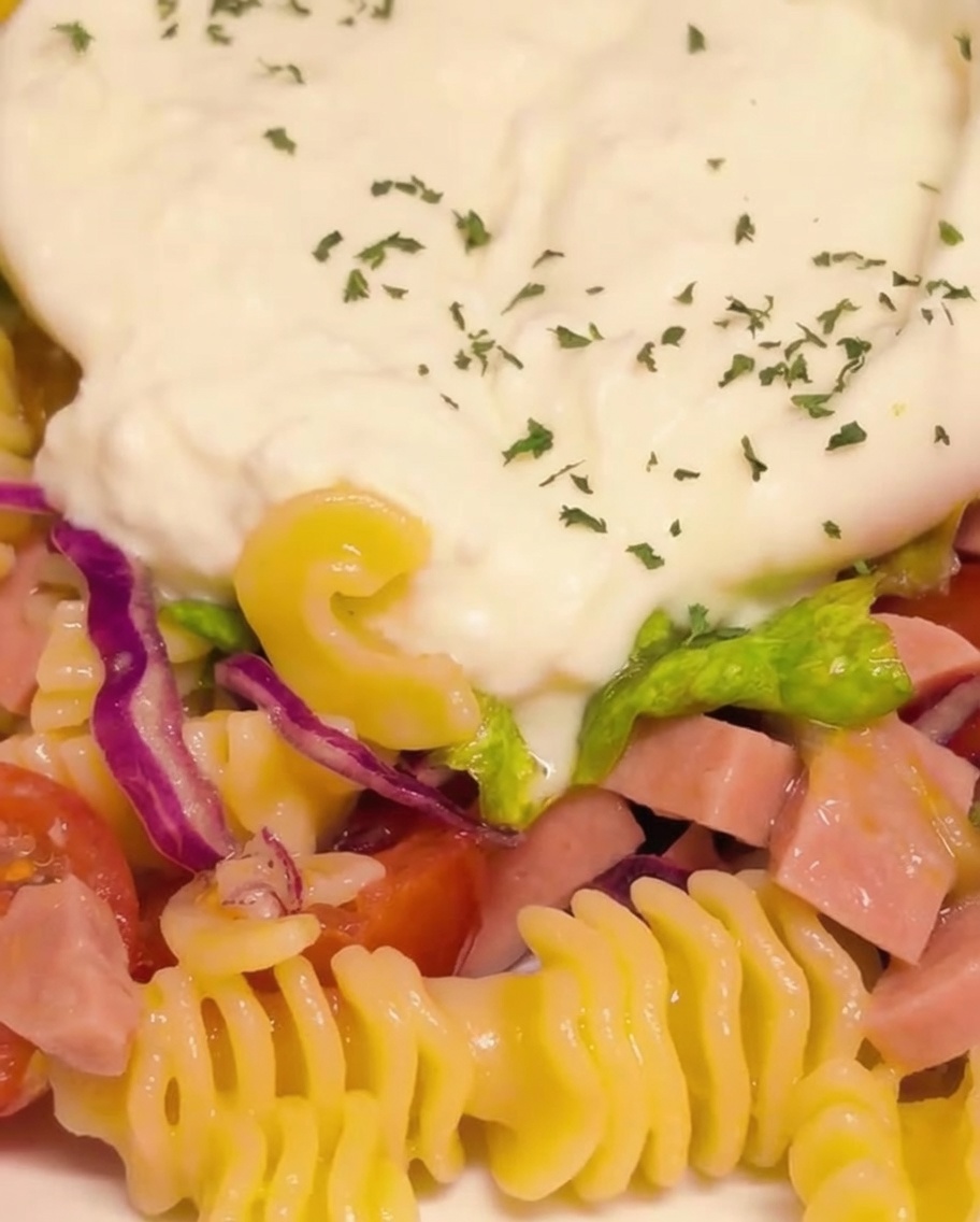 Primo piano della burrata cremosa aperta e condita con prezzemolo verde e scaglie di peperoncino.