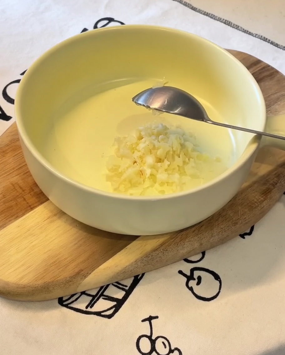 Aglio, cipollotto, maionese, tuorlo e condimento in una ciotola gialla.