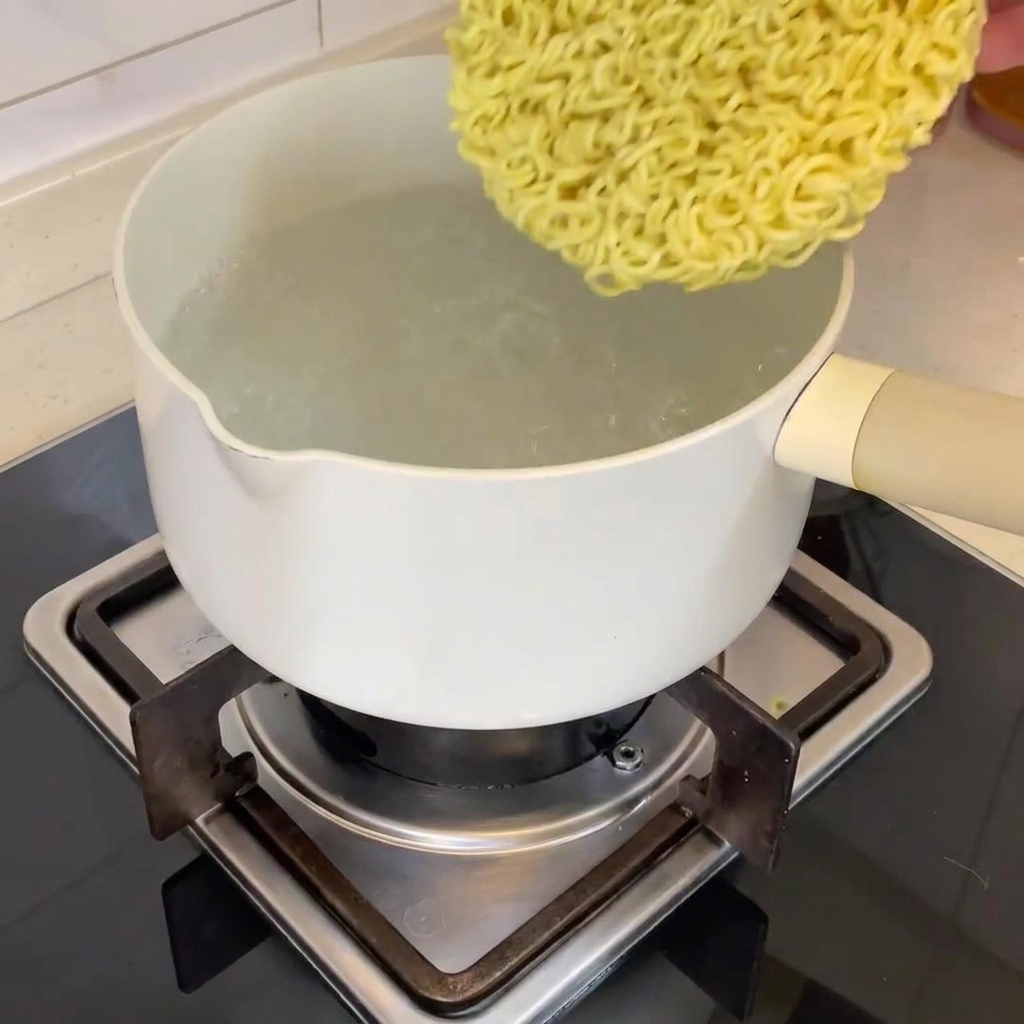 Noodles ramen secchi immersi nellacqua bollente.