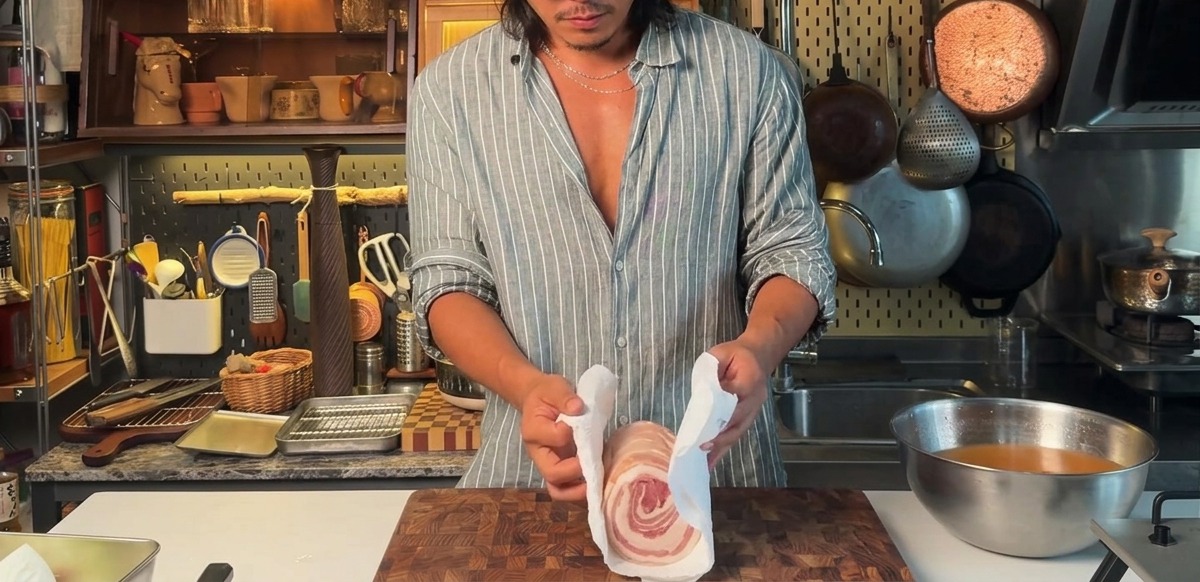 Asciugare una pancetta di maiale legata e marinata con carta assorbente.