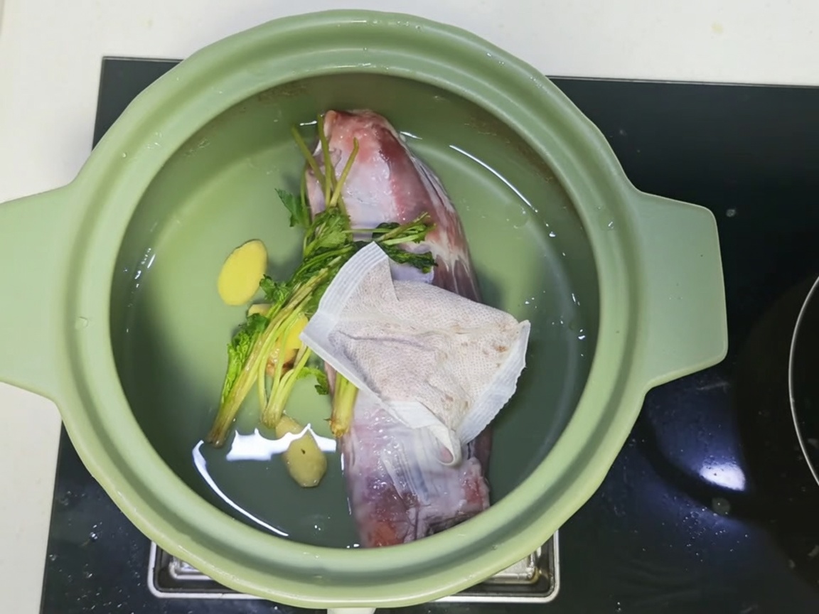 Tegame di terracotta riempito con carne, spezie e un brodo scuro e saporito.