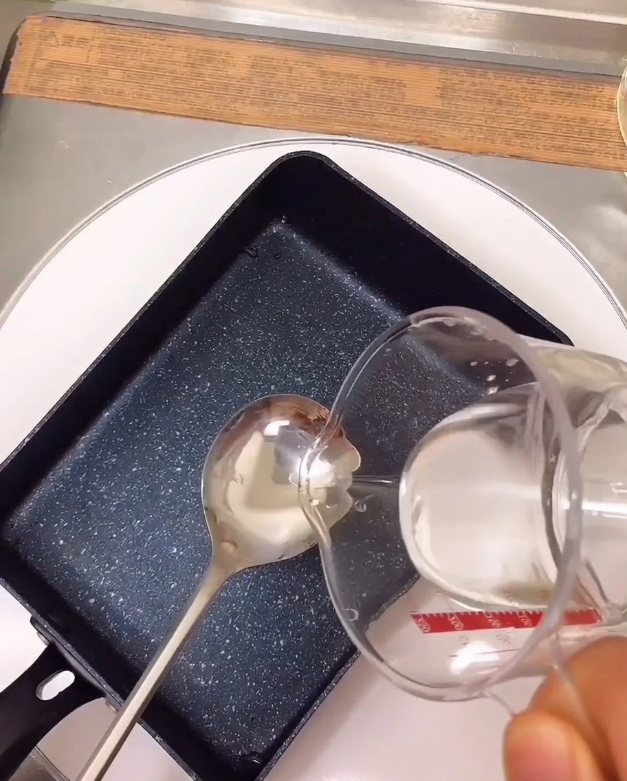 Gli ingredienti della marinatura cuociono a fuoco lento in una padella rettangolare sul fornello.