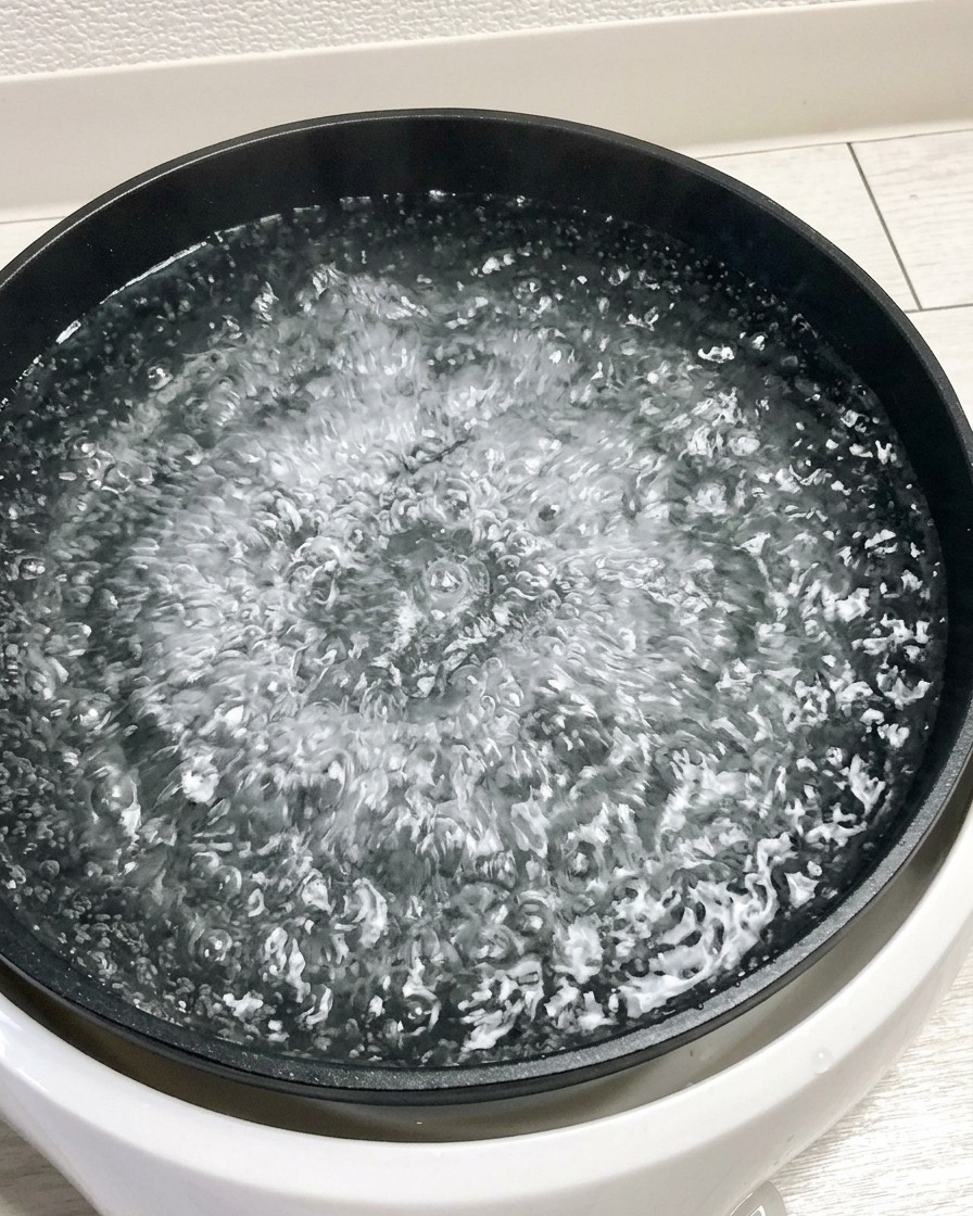 Cinque uova crude vengono immerse in una grande pentola di acqua bollente.