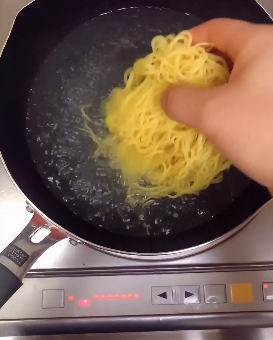 Noodles gialli per ramen bollono in una pentola dacqua sul fuoco.