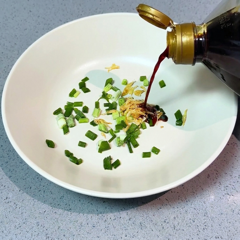 Versare la salsa di soia chiara sui cipollotti e i gamberetti.