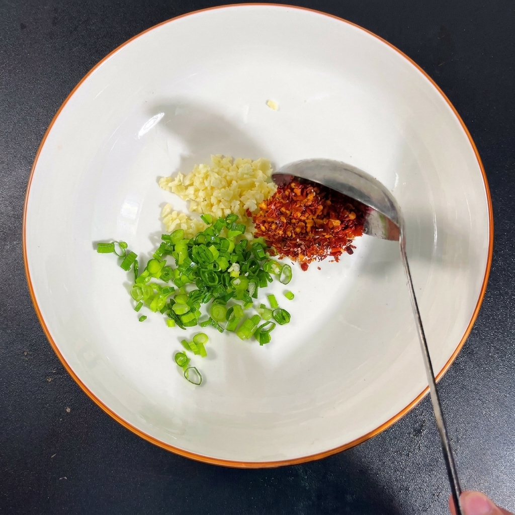 Una ciotola con aglio, cipollotti, sale, MSG, peperoncino e salsa di soia.