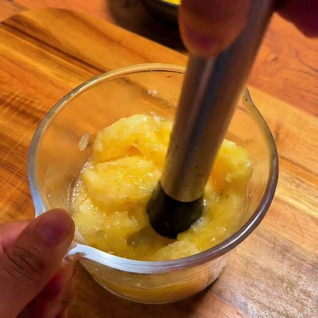 Uno spremiagrumi in metallo estrae il succo giallo vibrante dello yuzu in un misurino di vetro.