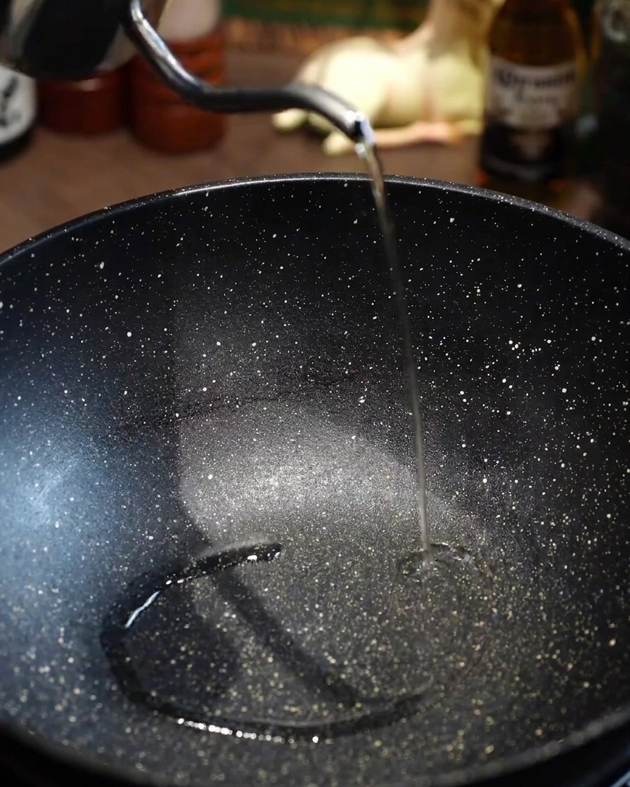Olio di semi versato in una padella nera vuota preriscaldata.