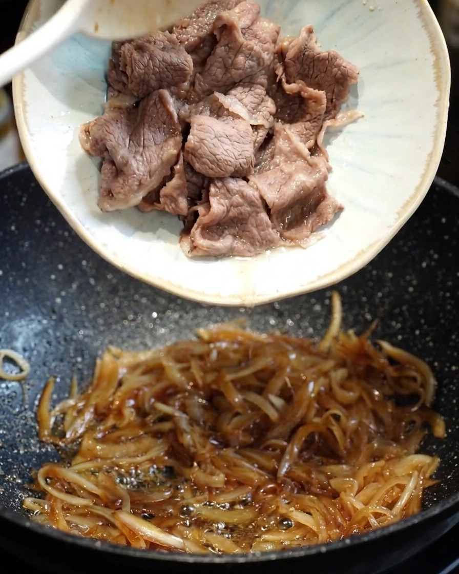 Salsa teriyaki scura e saporita versata in padella con cipolle e manzo.