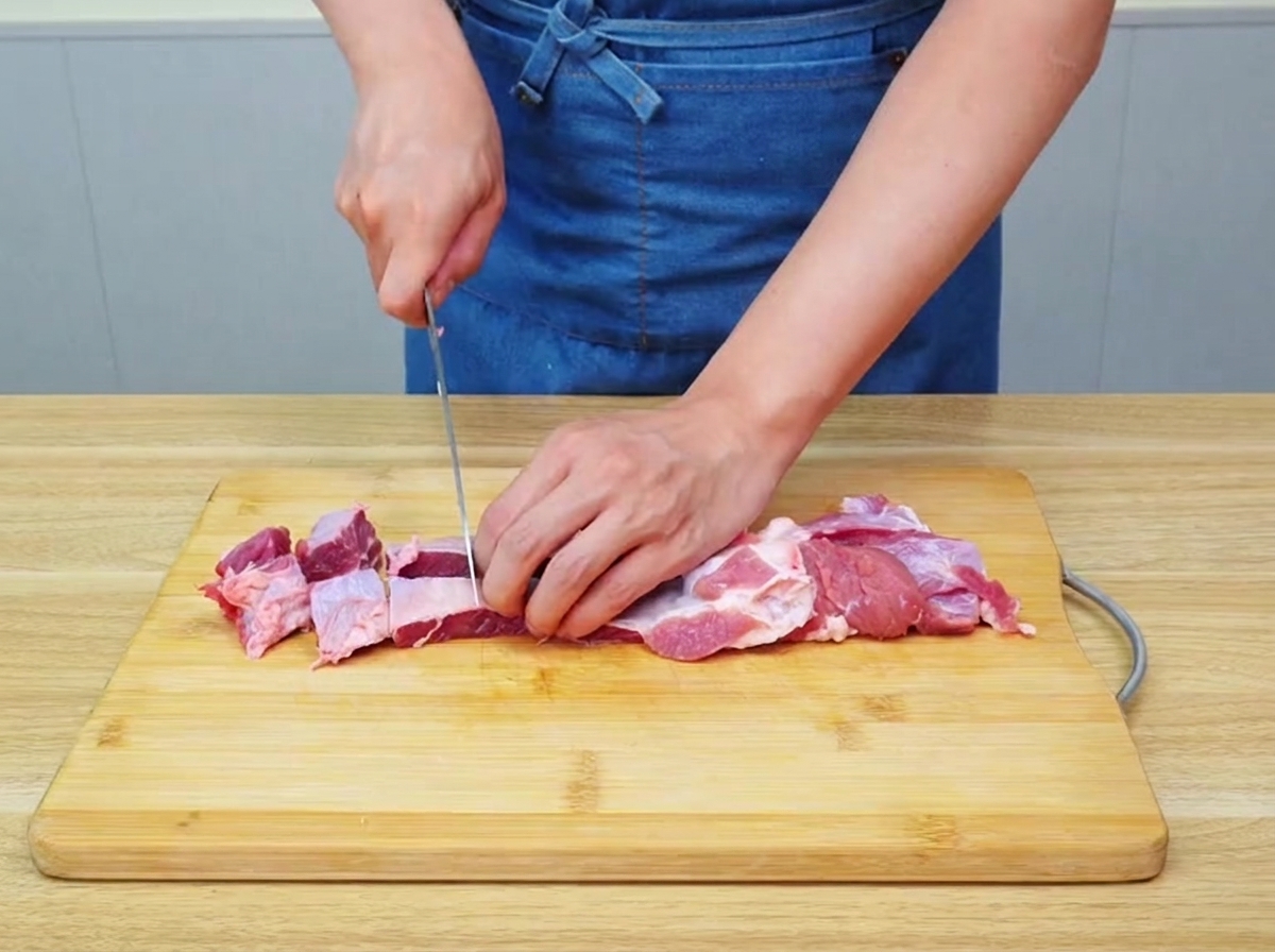 Punta di petto di manzo cruda tagliata con cura in grossi pezzi uniformi su un tagliere di legno.