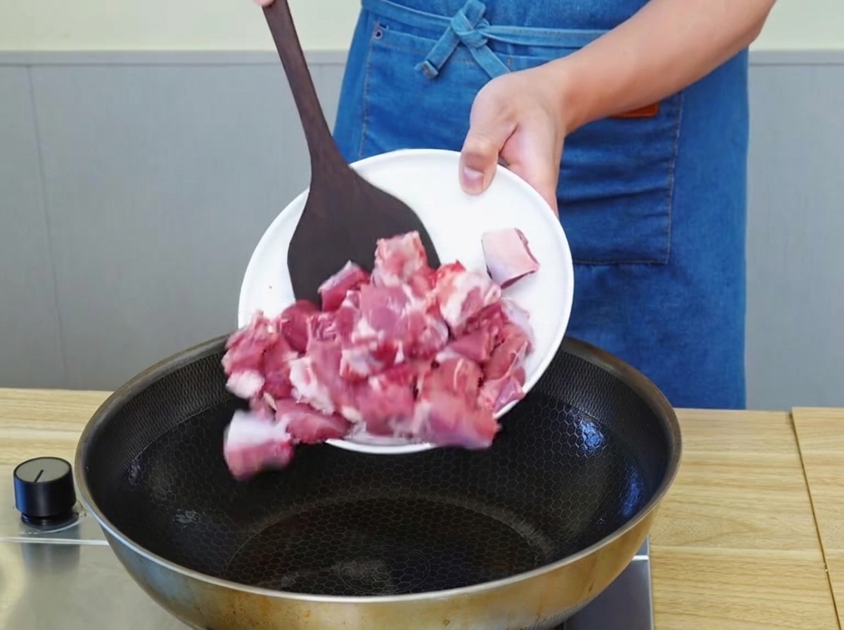 Pezzi di manzo che rosolano in padella con olio caldo, formando una crosticina dorata.