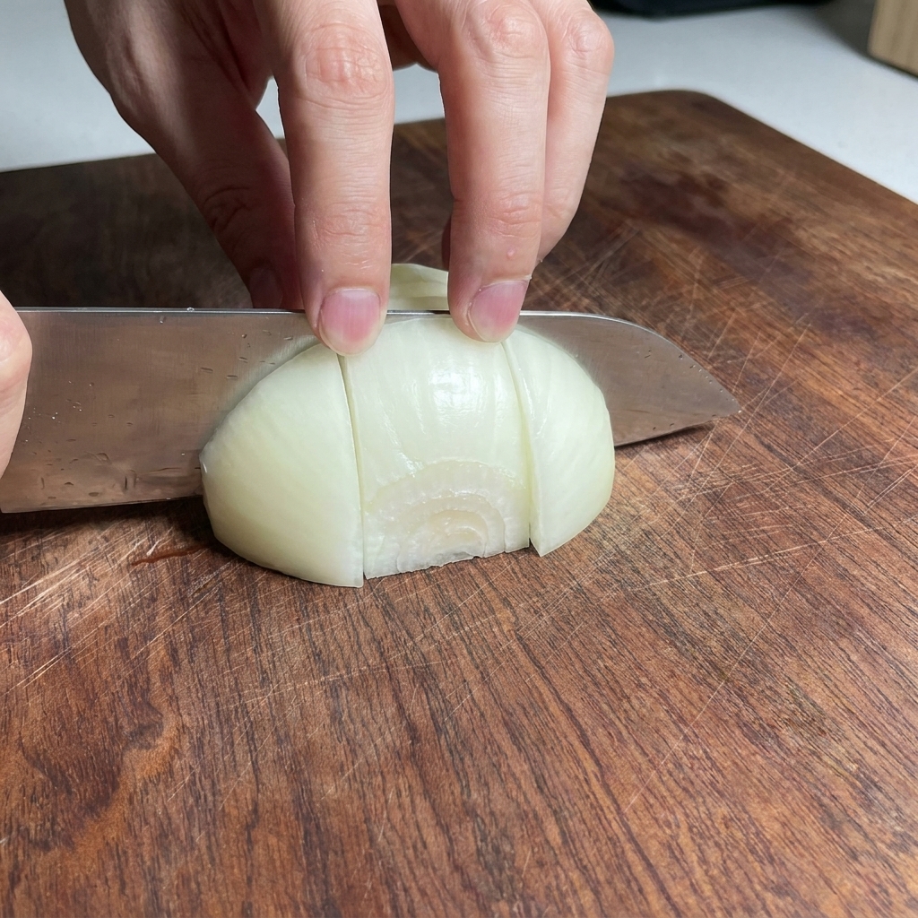 Pezzi di cipolla tagliati grossolanamente su un tagliere di legno.
