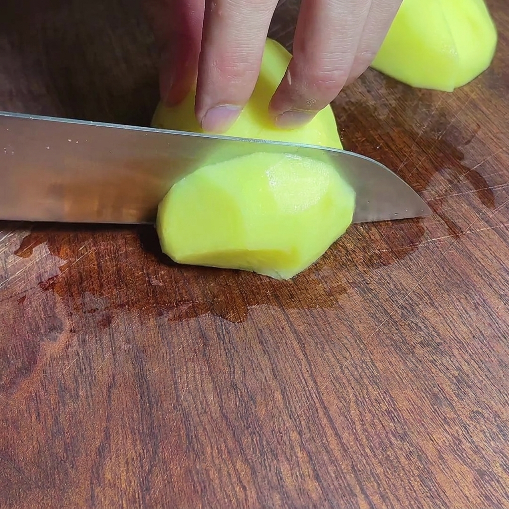 Pezzi di patata tagliati su un tagliere di legno.