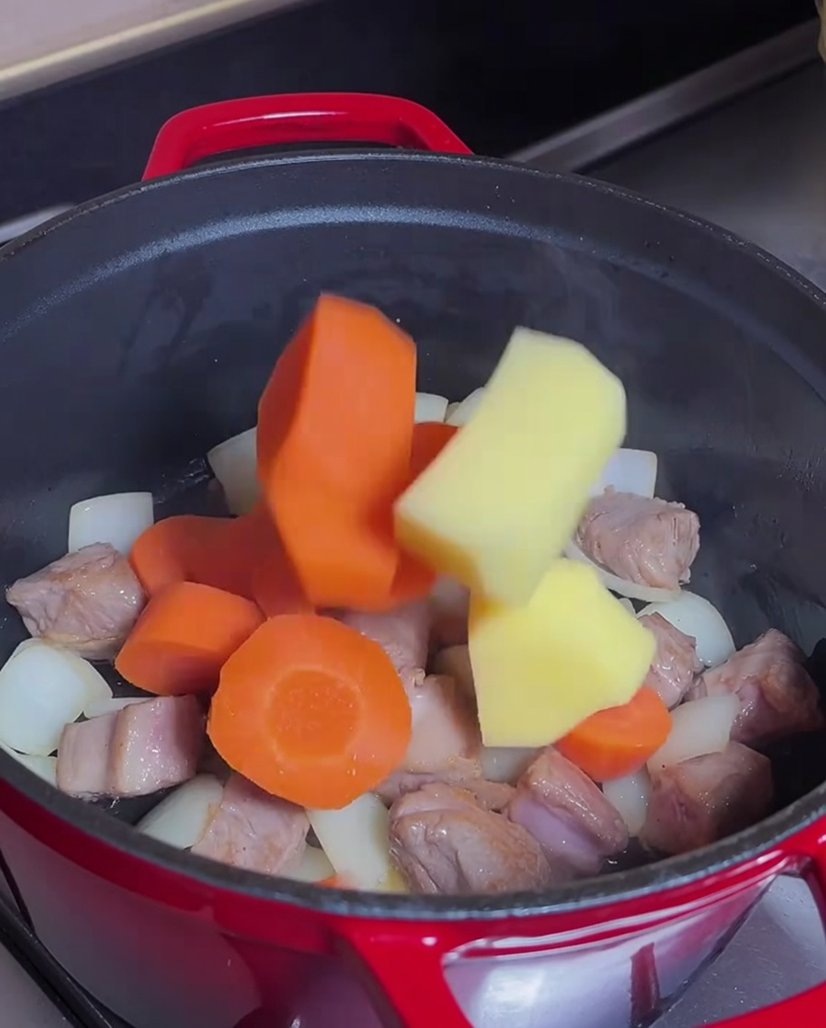 Carote e patate mescolate nella pentola con la carne rosolata.