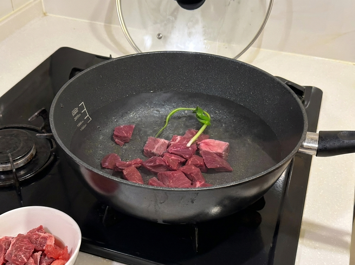 Bocconcini di manzo che sobbollono in una pentola con aromi e vino da cucina.