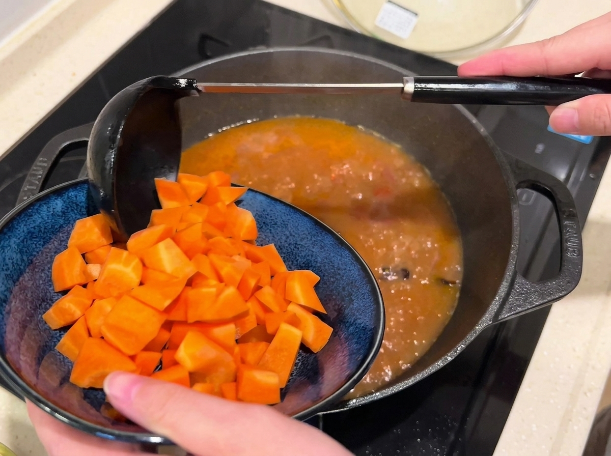 Carote a dadini aggiunte in una padella di brodo di manzo che sobbolle.