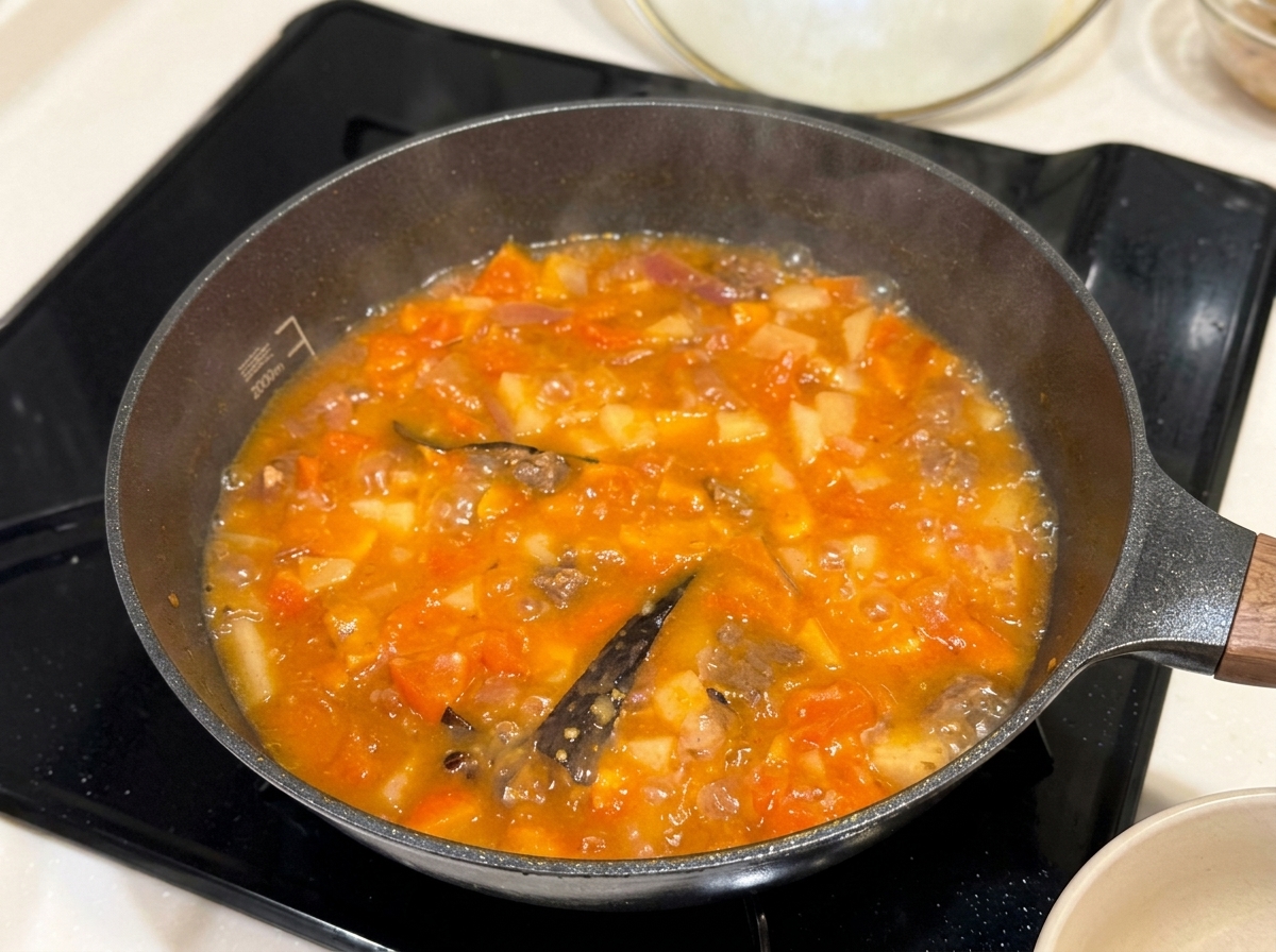 Cubetti di curry speziato posizionati in una padella di stufato che sobbolle.