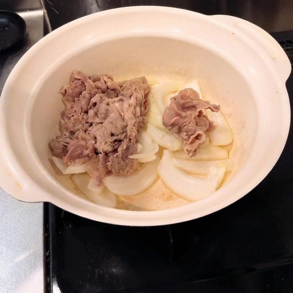 Manzo sbollentato mescolato con le cipolle in una pentola.