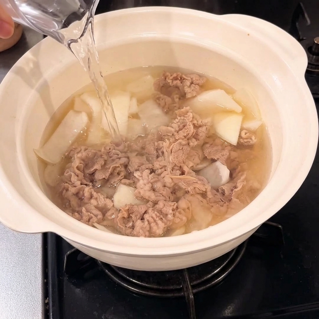 Acqua versata nella pentola con il composto di manzo e cipolla.