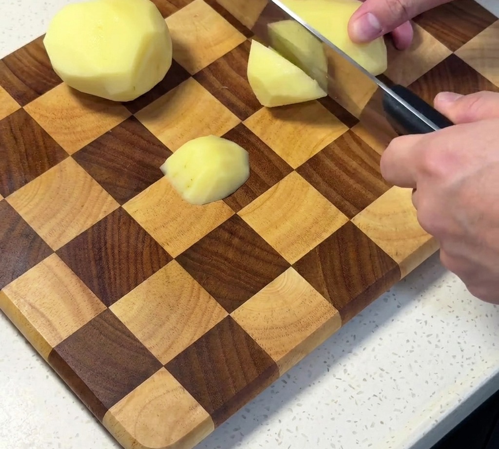 Patate sbucciate e tagliate a cubetti su un tagliere.