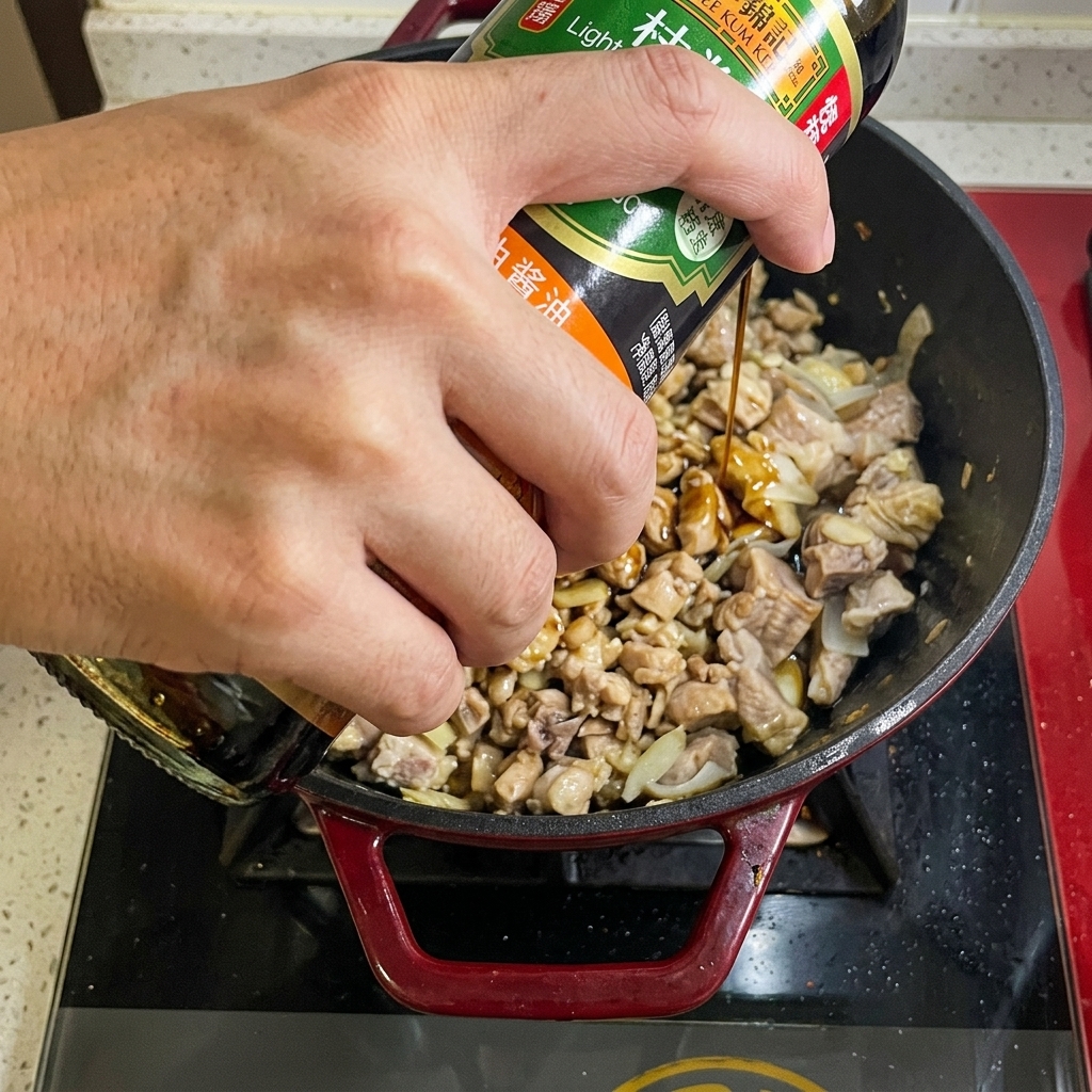 Salsa di soia versata da una bottiglia nella padella con il manzo.
