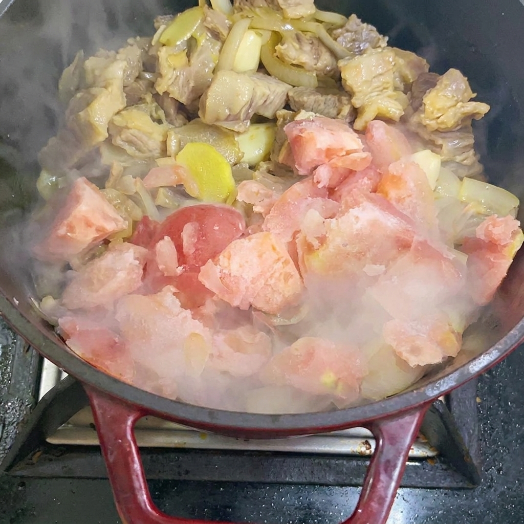Aggiunta di pezzi di pomodoro congelati nella padella di cottura.