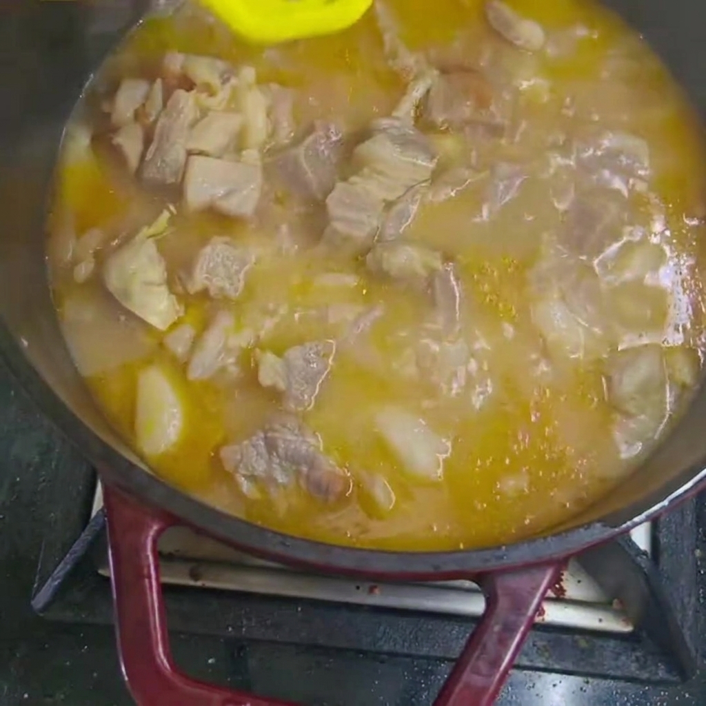 Pezzi di carota e patata aggiunti allo stufato di manzo che bolle nella pentola.