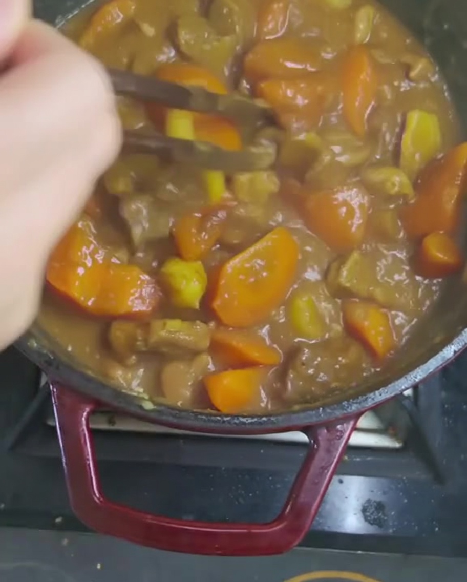 Mescolare la salsa di curry densa con un utensile di legno per sciogliere completamente i cubetti.