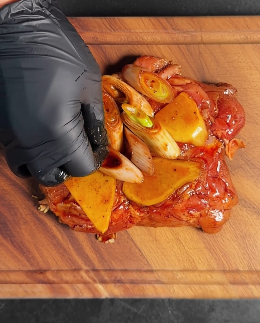 I pezzi di coscia di pollo ricoperti di marinata e aromi allinterno di una ciotola di metallo.