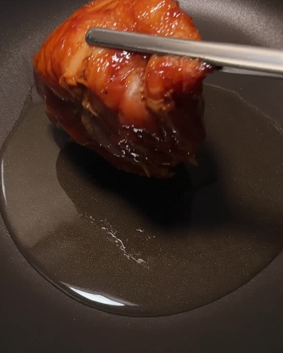 La coscia di pollo che frigge in una padella, focalizzandosi sulla pelle croccante.