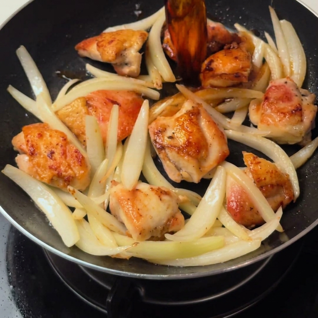 Pollo e cipolle che sobbollono nella salsa a base di dashi allinterno della padella.