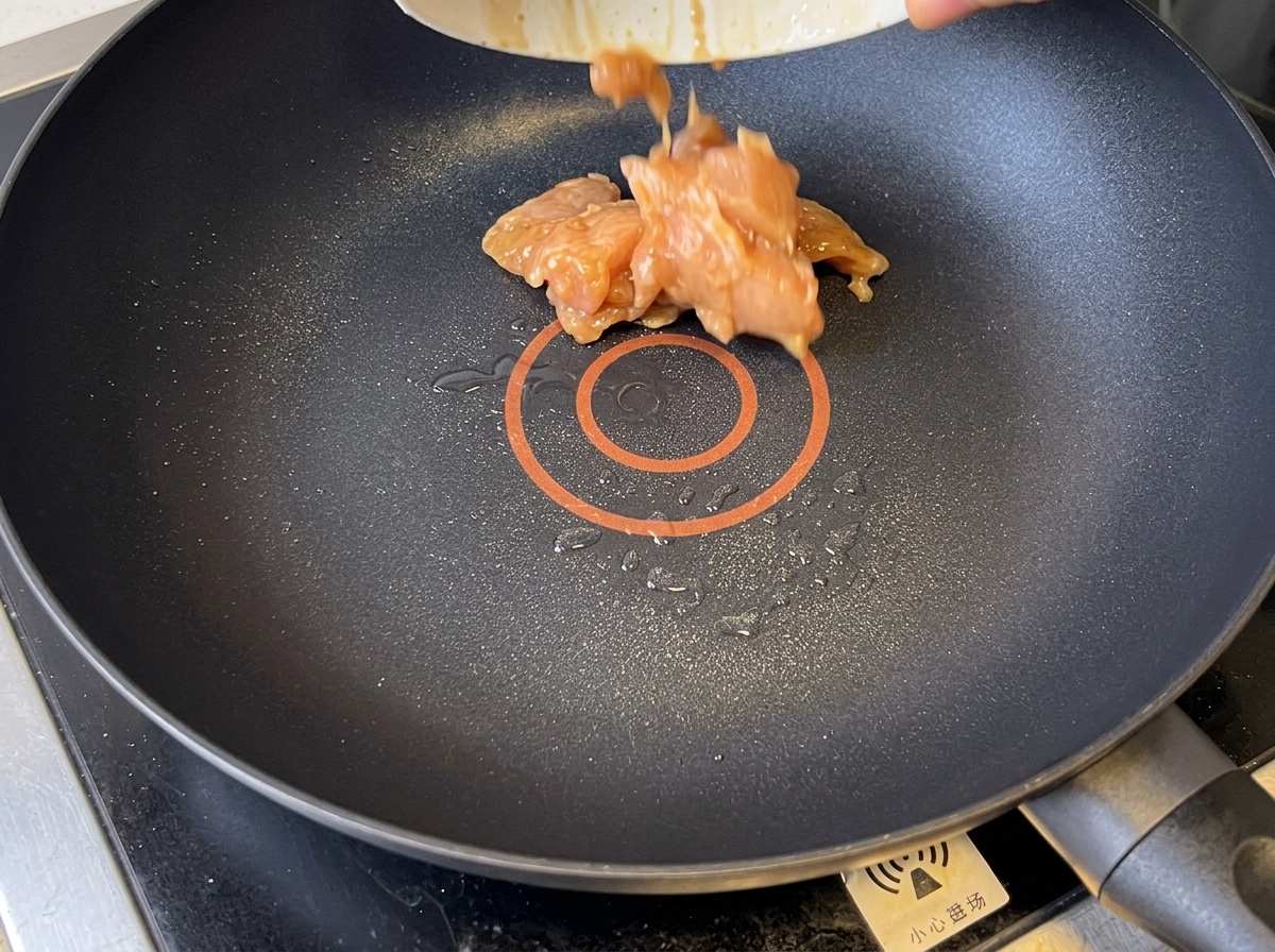 Pezzi di pollo dorati saltati in una padella antiaderente.