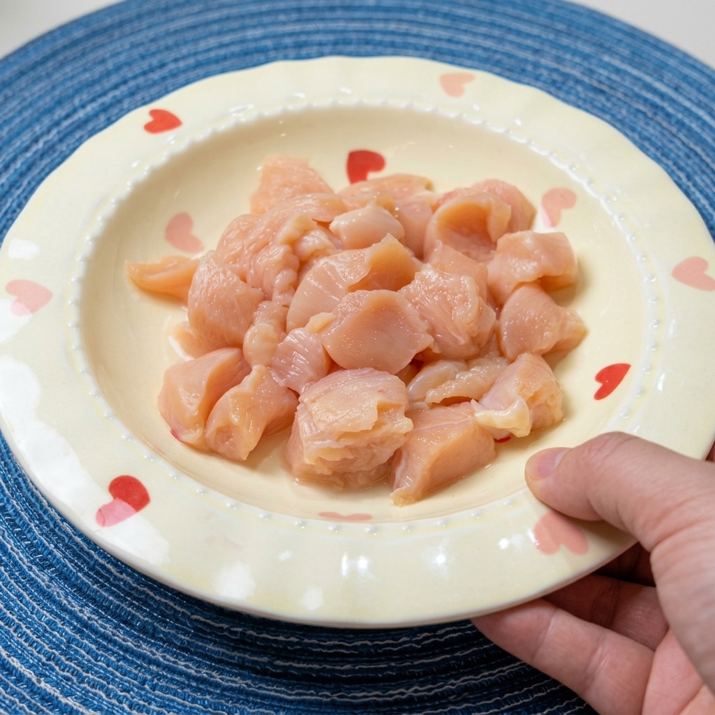 Petto di pollo tagliato a dadini in una ciotola, condito con salsa di soia, vino e spezie.