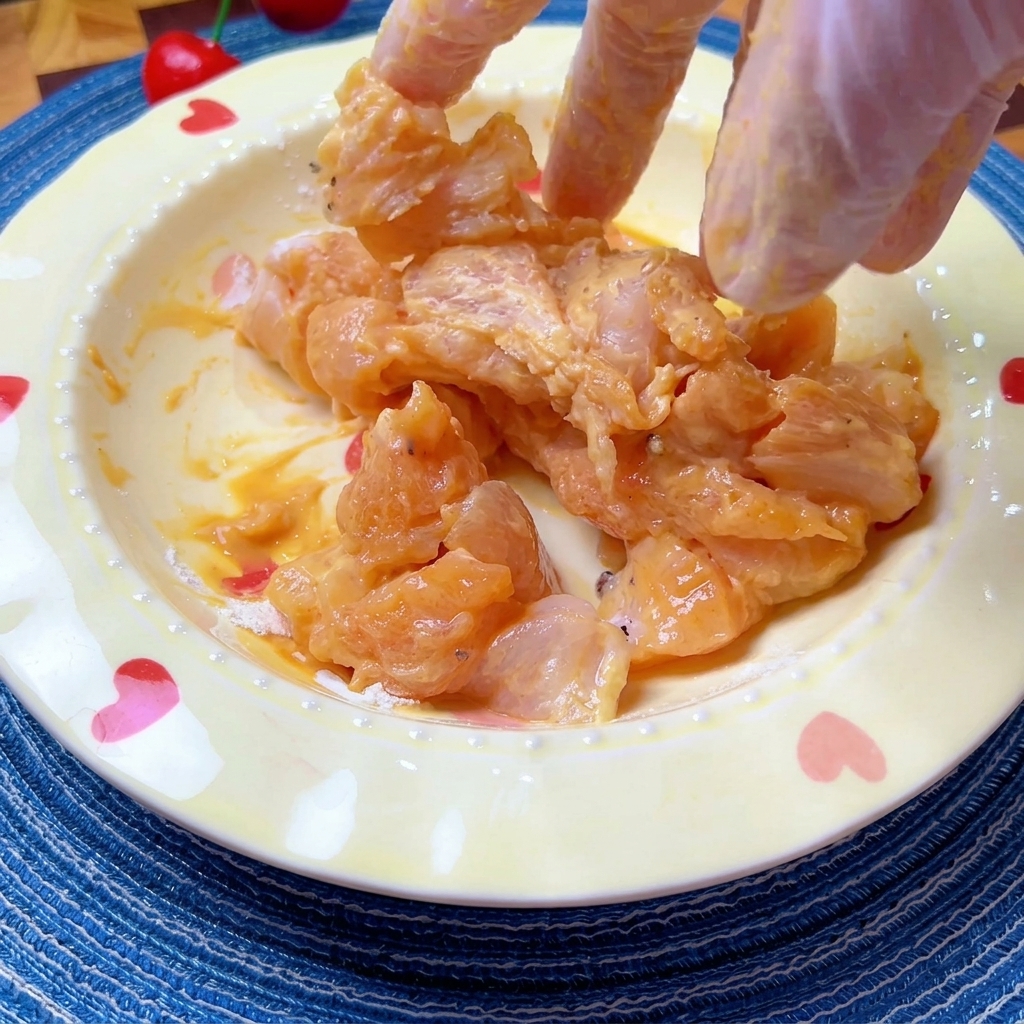 Pezzi di pollo marinati mescolati a mano in una ciotola.