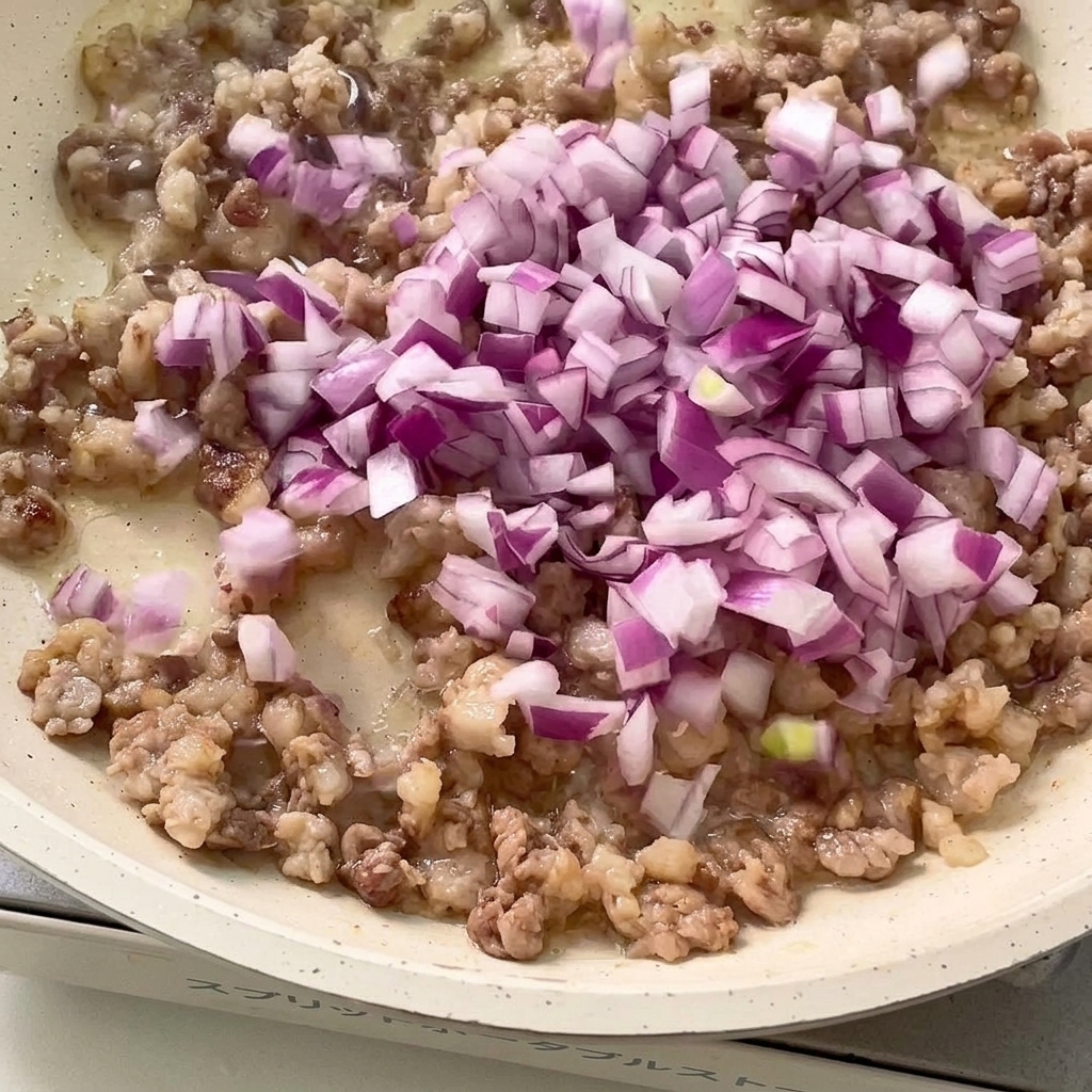 Cipolla rossa tritata e aglio tritato saltati in padella con la carne rosolata.