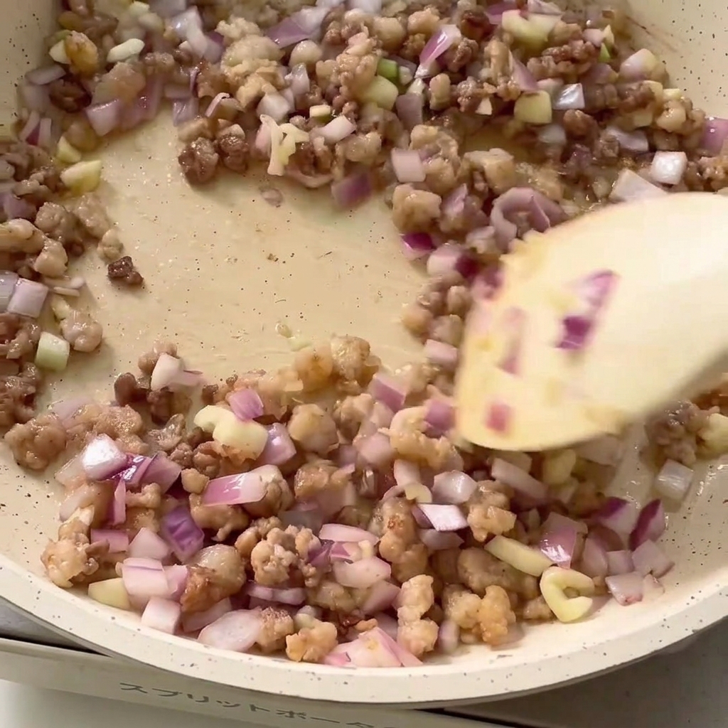 Ingredienti per il condimento aggiunti alla padella con carne macinata e cipolla.