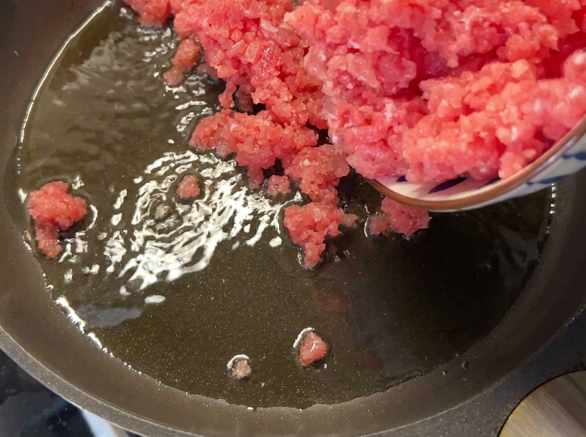 Macinato di maiale magro aggiunto in una padella calda e oleata.