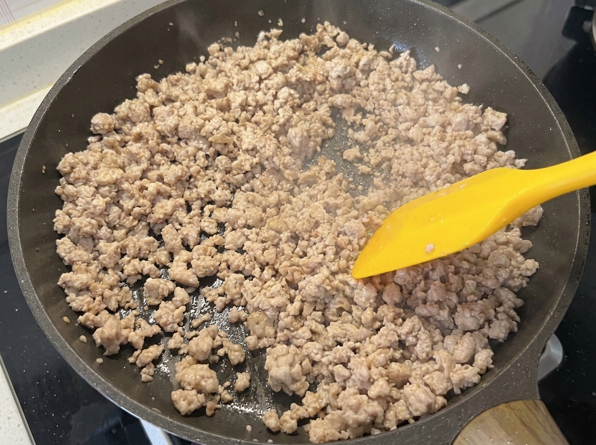Il macinato di maiale in padella, che appare dorato e asciutto dopo la cottura.