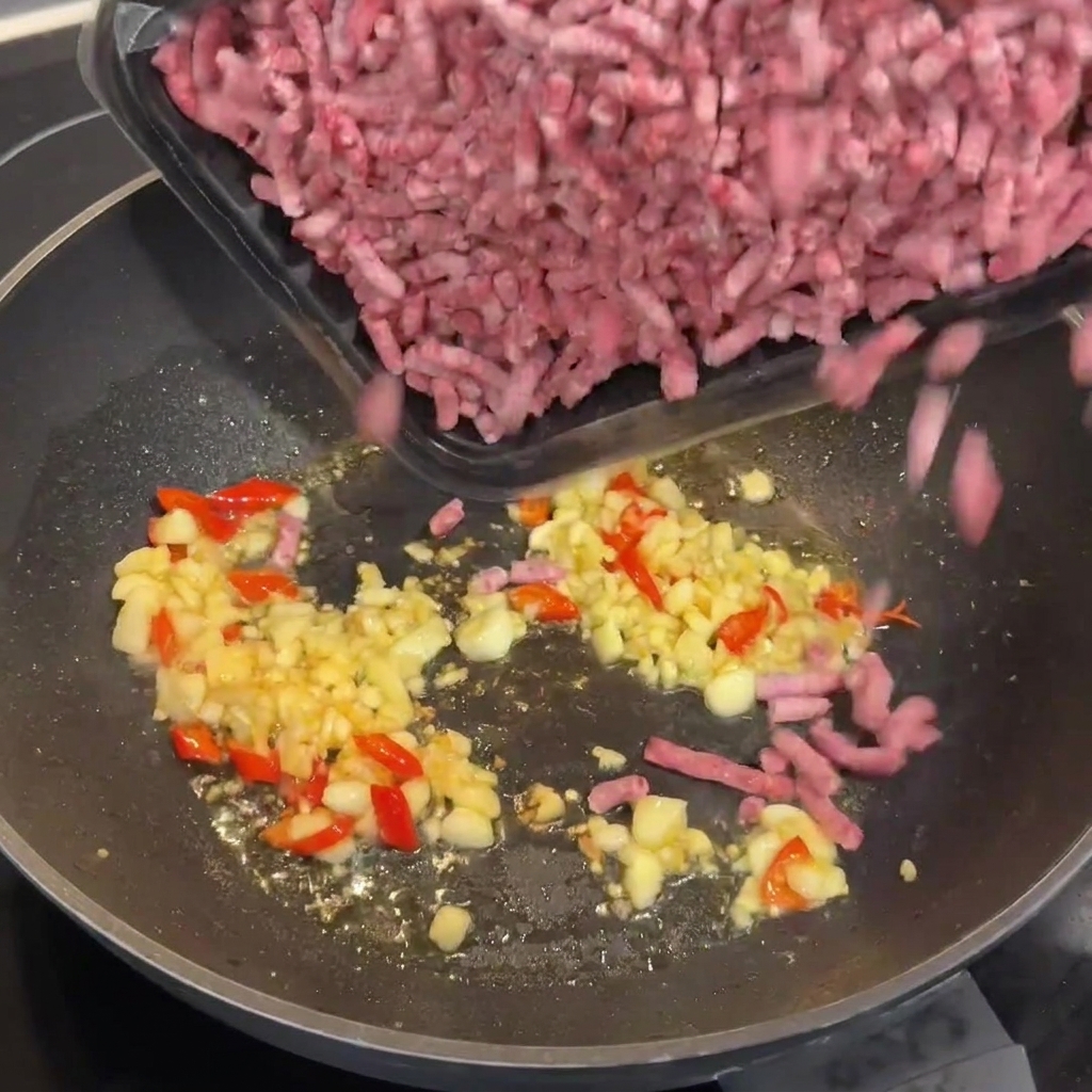 Macinato di manzo Wagyu crudo aggiunto al wok caldo con laglio e i peperoncini rosolati.