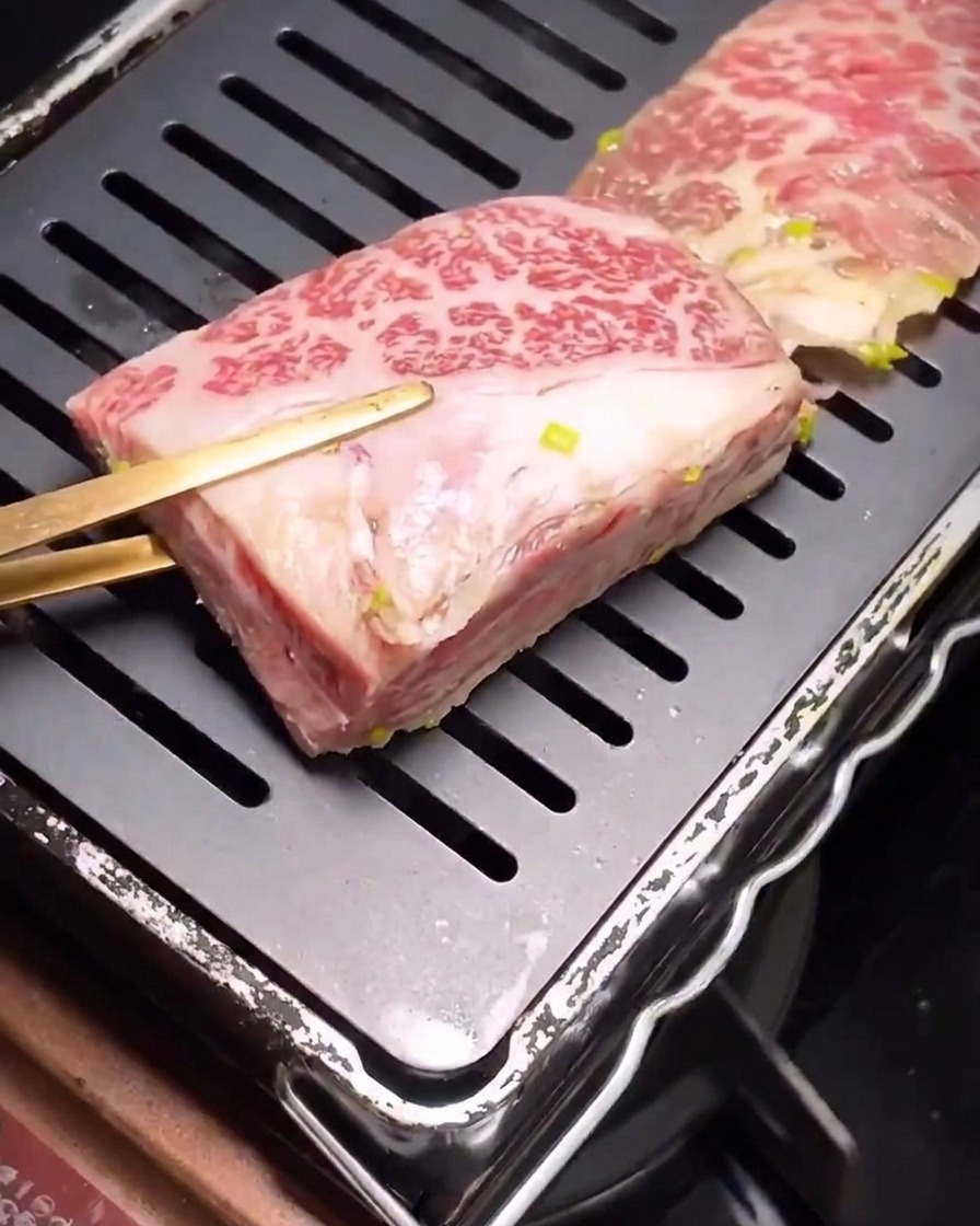 Costine di manzo marinate che iniziano a rosolare su una bistecchiera nera con scanalature.