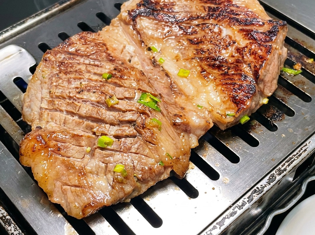 Primo piano di costine di manzo in stile coreano tagliate in pezzi più piccoli con le forbici su una bistecchiera calda.