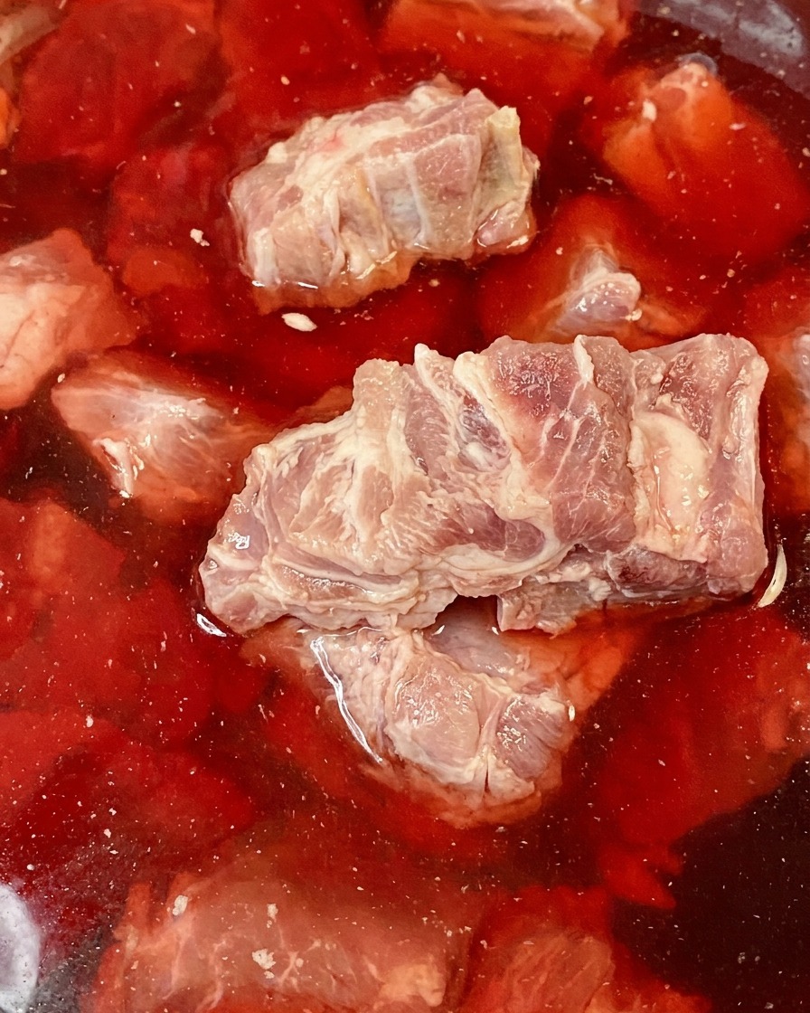 Ossa di maiale crude immerse in una ciotola di acqua arrossata dal sangue.