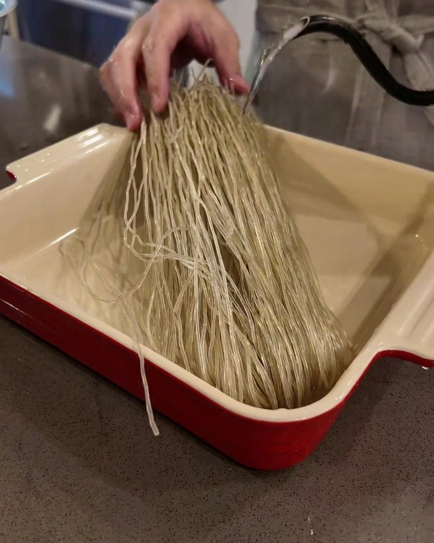 Noodles di fecola di patate dolci secchi a bagno in una teglia riempita dacqua tiepida.