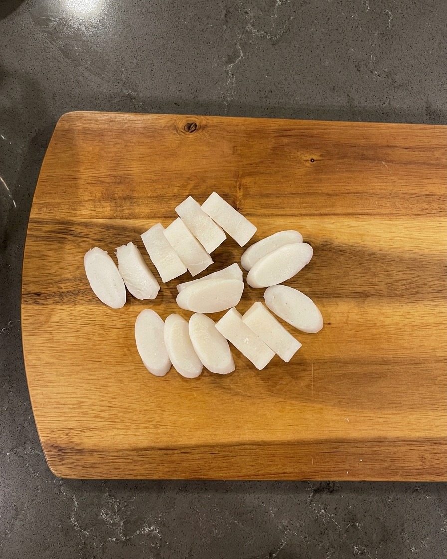 Primo piano di costine di manzo cotte e pezzi di ravanello messi in una piccola pentola di pietra nera resistente.