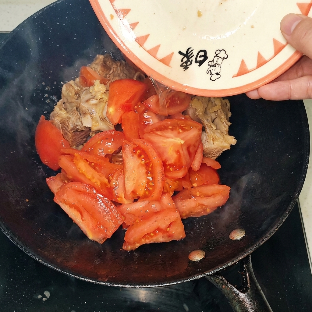 Pezzi di pomodoro pelato aggiunti al wok con le costine.