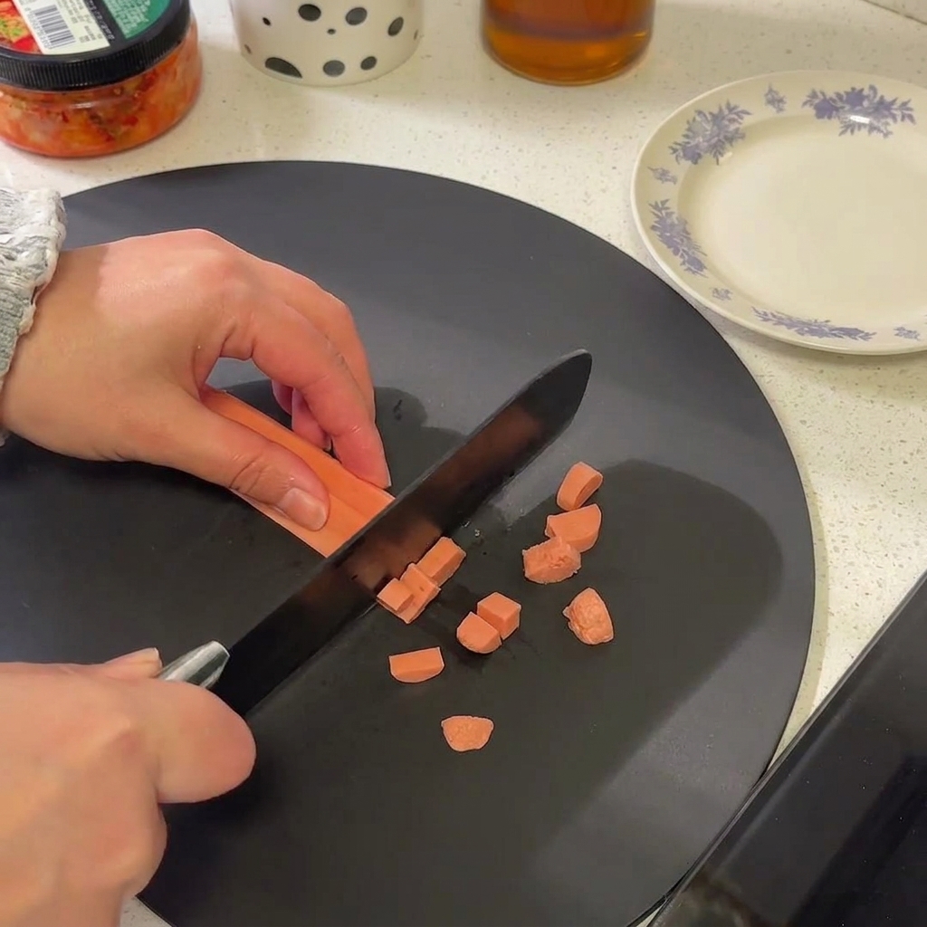 Un primo piano di una salsiccia tagliata a rondelle su un tagliere nero.
