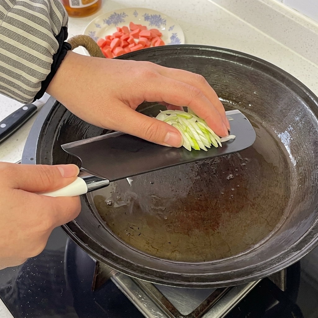Rondelle di salsiccia e cipollotti tritati che sfrigolano in una padella calda.