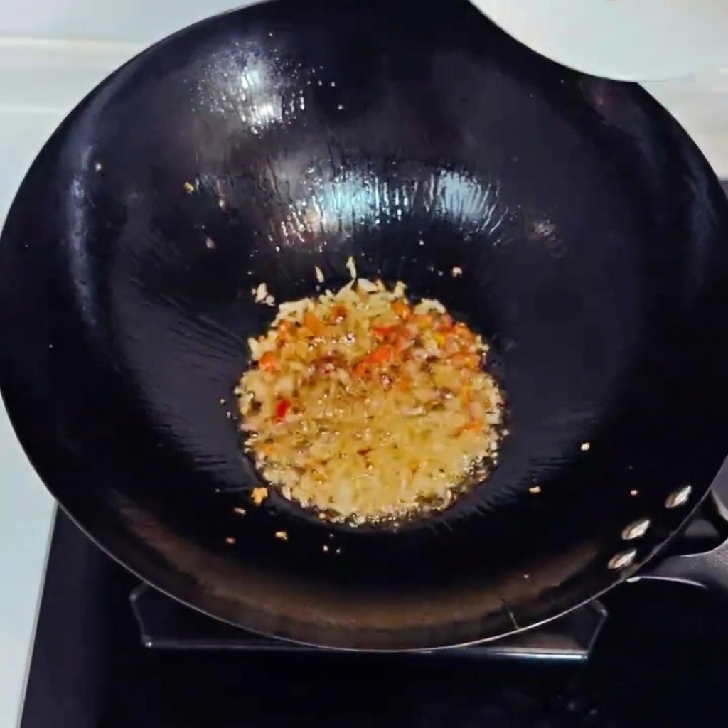 Kimchi tritato e prosciutto a cubetti saltati in padella in un wok con gli aromi.