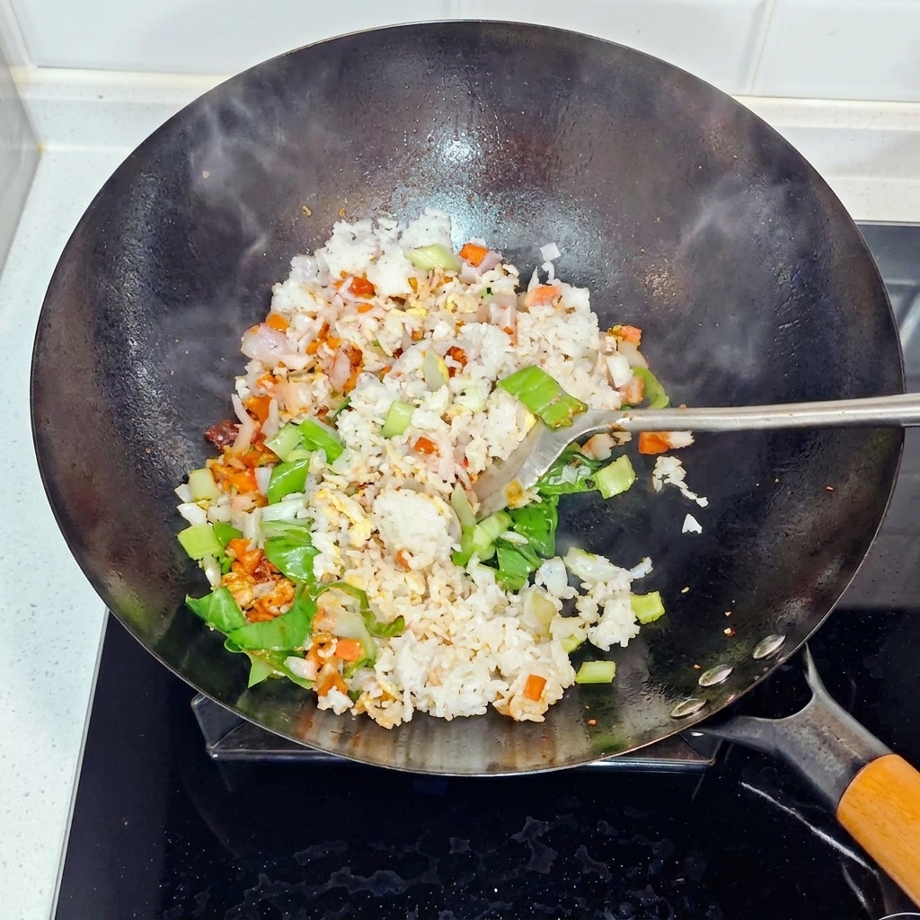 Riso, cipolle e bok choy saltati e mescolati in un wok.