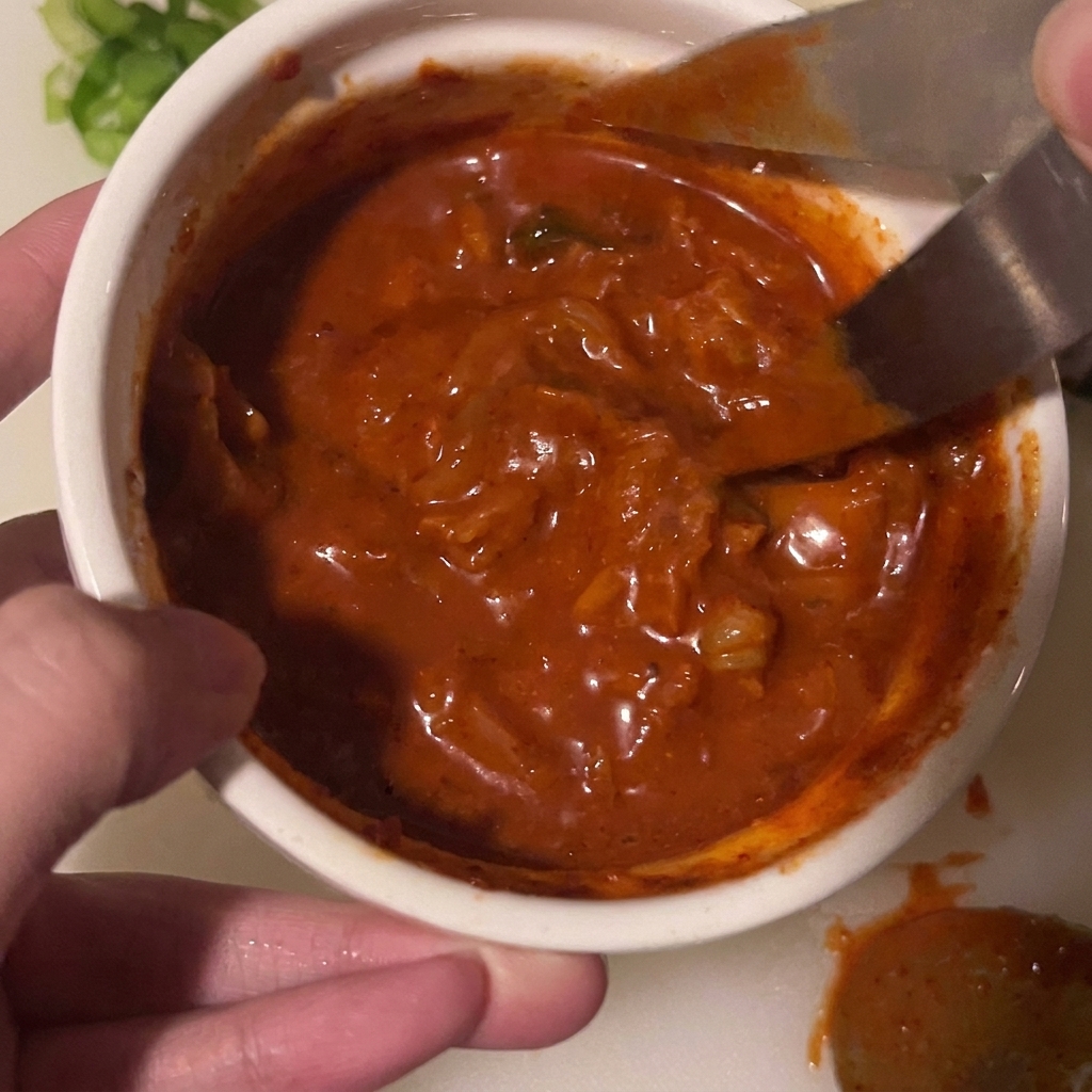 Un paio di forbici che tagliano pezzi di kimchi direttamente allinterno di una ciotola con la salsa.